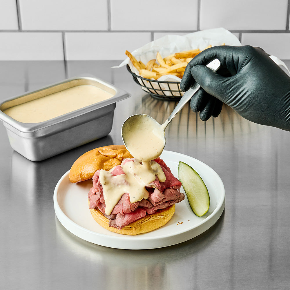 pouring alabama white sauce on a dish