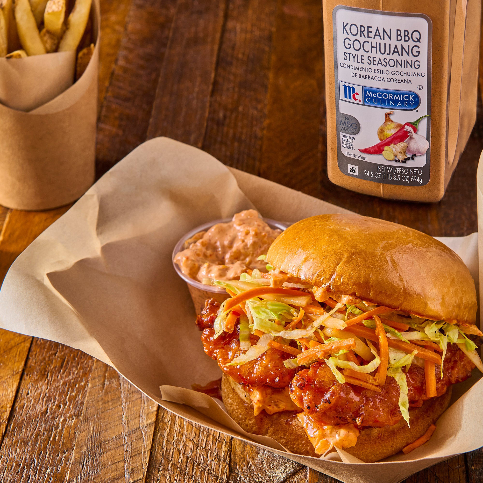 fried chicken sandwich and french fries on a wooden table with korean bbq gochujang style seasoning