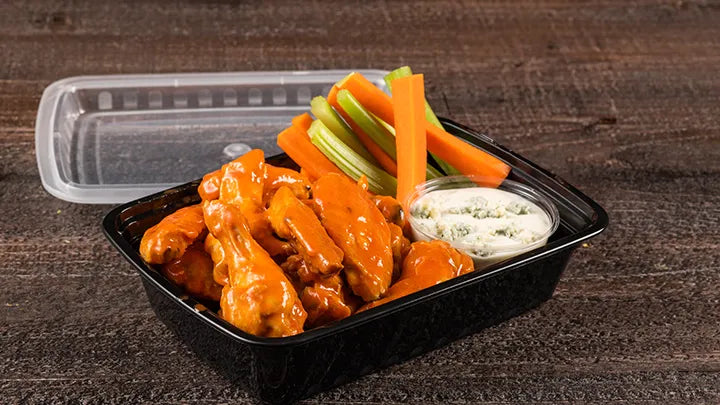 saucy chicken wings in a black to go container