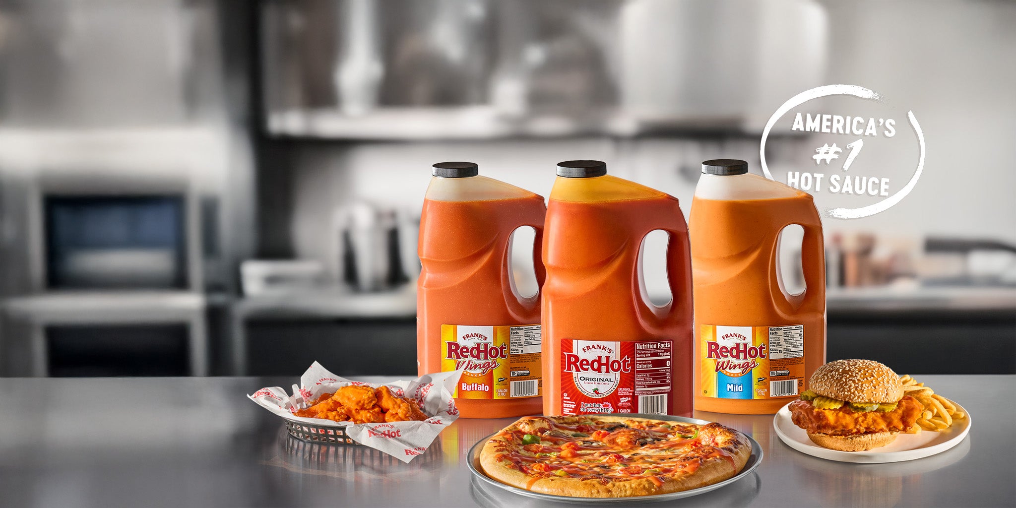 Three bottles of RedHot hot sauce on a kitchen counter with food items.