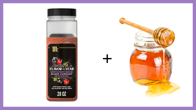 Bottle of black currant flavoring with a jar of honey and honey dipper on a white background