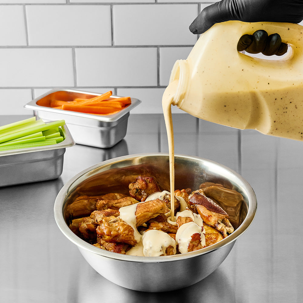 pouring alabama white sauce on a dish