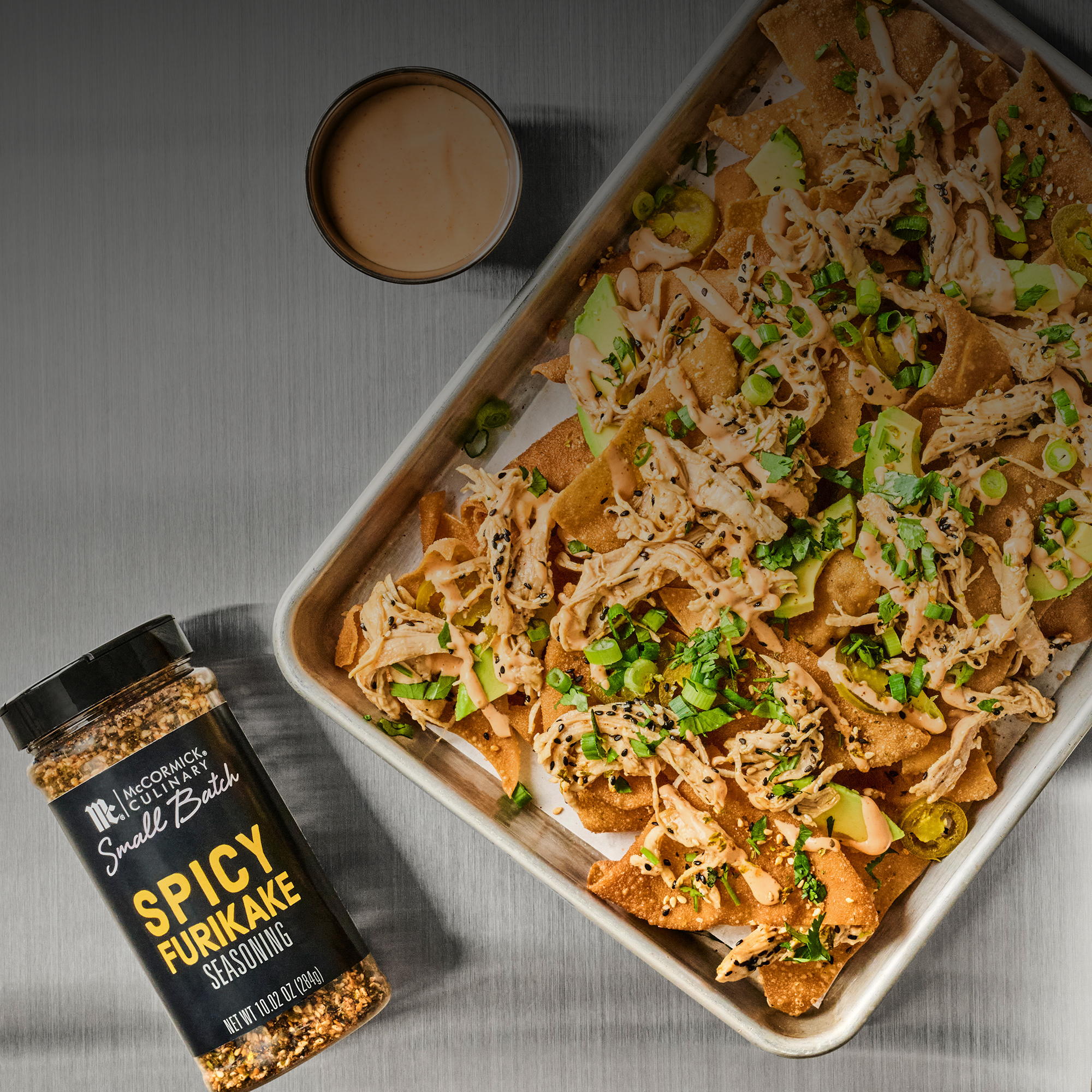 Spicy Furikake seasoning bottle with a tray of nachos on a gray surface