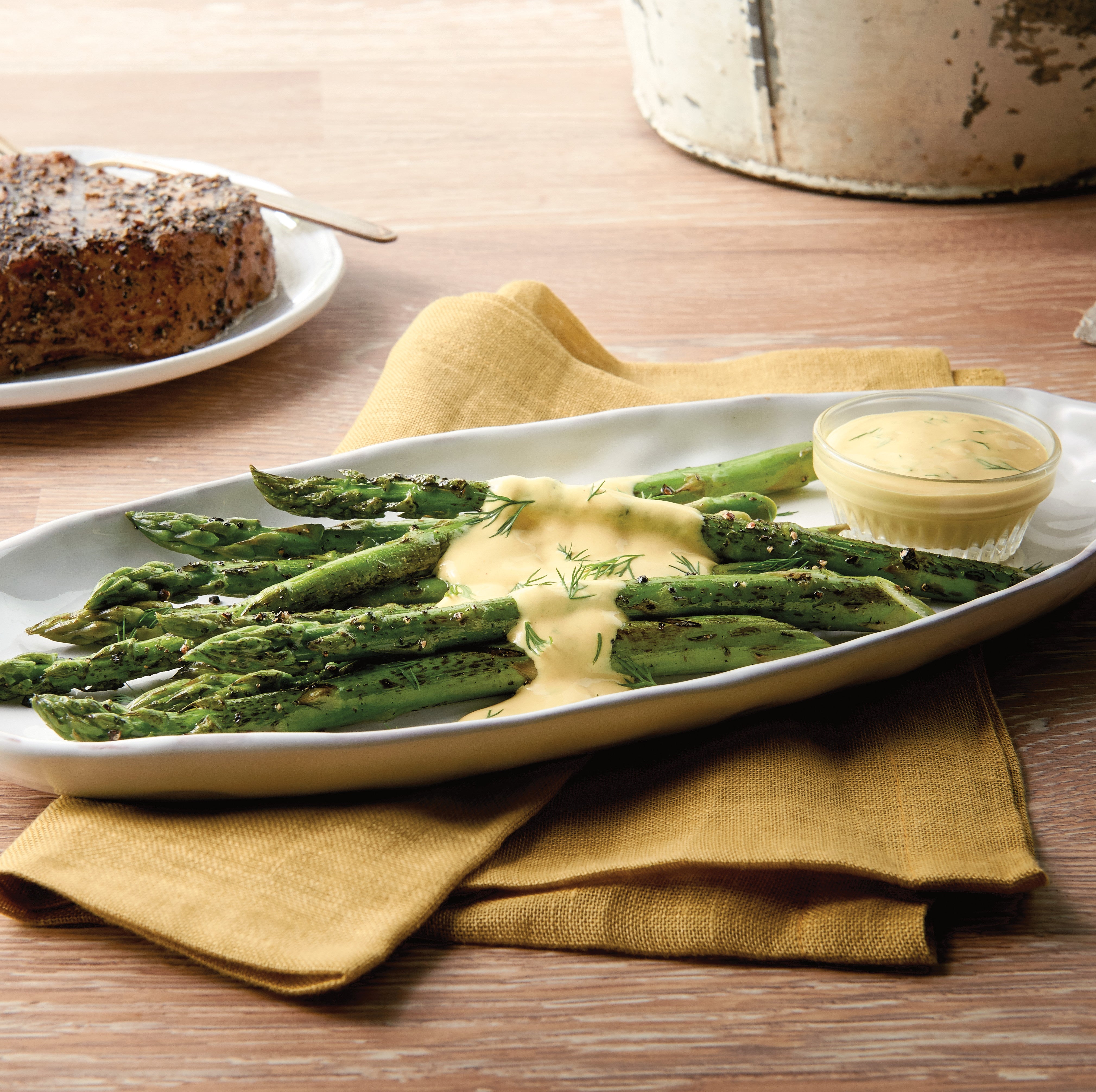 Platter of asparagus with a creamy sauce on a wooden table